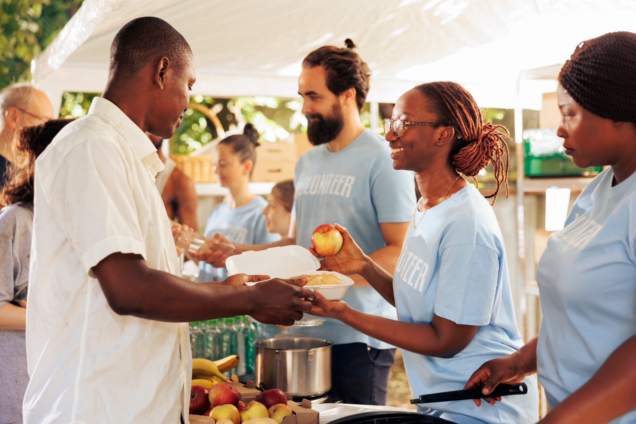 Volunteers serving food and fruit to people at a community event.